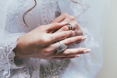 Description: Texas bride touches her wedding ring on finger in front of white lace wedding dress