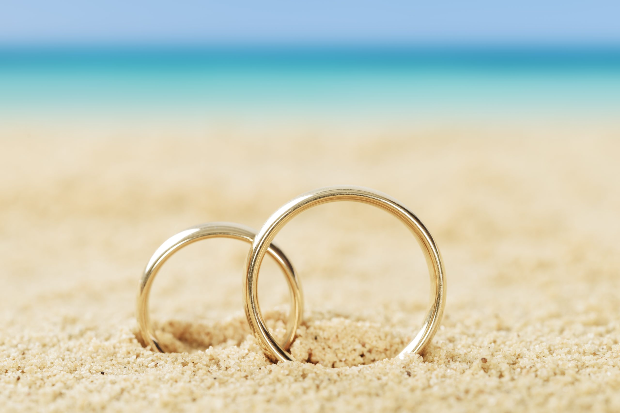 Photos of wedding rings on sand at beach