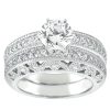 A white gold engagement ring features a large round diamond center stone surrounded by smaller diamonds and intricate filigree detailing.