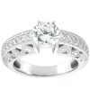 A silver engagement ring features a large round diamond surrounded by smaller diamonds and intricate detailing on the band.