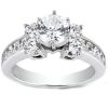 A silver ring with a large central diamond and smaller diamonds on either side, featuring a row of smaller stones on the band.