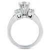 A silver engagement ring features a large central diamond flanked by two smaller diamonds.