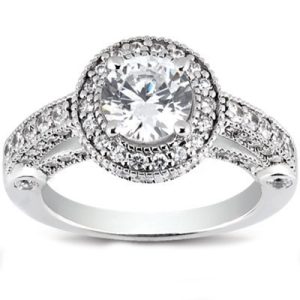 A silver ring with a large round diamond surrounded by smaller diamonds on a decorative band.