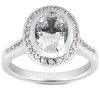 A silver ring features a large oval diamond surrounded by smaller gemstones.