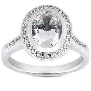 A silver ring features a large oval diamond surrounded by smaller gemstones.