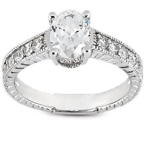 A silver ring with an oval diamond center stone and smaller diamonds set along the band.