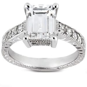 An emerald-cut diamond ring with a silver band and smaller diamonds set along the sides.