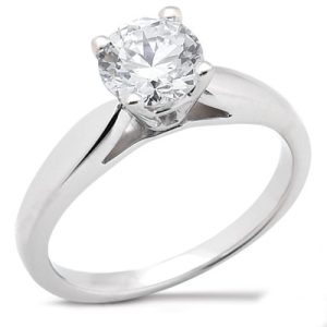 A silver ring features a large round diamond at its center.