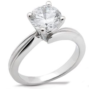 A silver engagement ring features a large, round, clear diamond set in a four-prong mounting.
