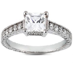 A silver engagement ring features a large square diamond surrounded by smaller sparkling stones on the band.