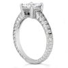 A silver engagement ring features a round central diamond surrounded by smaller accent diamonds on a textured band.