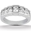 A silver ring features a row of round, clear gemstones set in a detailed band.