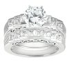 A set of silver engagement and wedding rings featuring a large round diamond surrounded by smaller princess-cut diamonds.