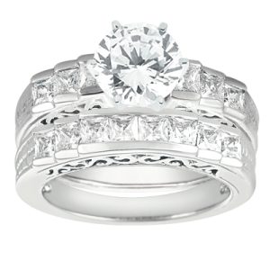 A set of silver engagement and wedding rings featuring a large round diamond surrounded by smaller princess-cut diamonds.