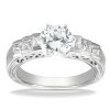 A silver engagement ring with a large round diamond center stone and four smaller square diamonds on either side.
