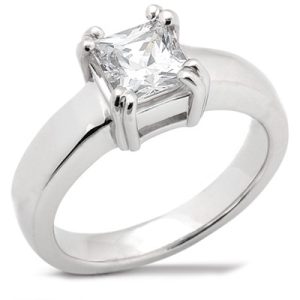 A silver engagement ring features a large, square-cut clear gemstone at its center.