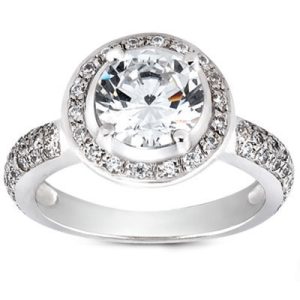 A silver ring features a large round diamond at the center, surrounded by smaller diamonds on the band.