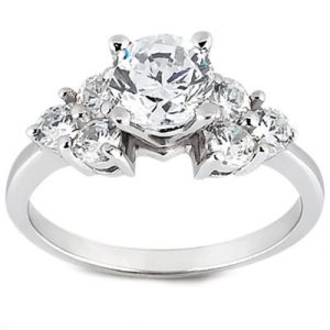 A silver ring with a central round diamond surrounded by smaller diamonds.