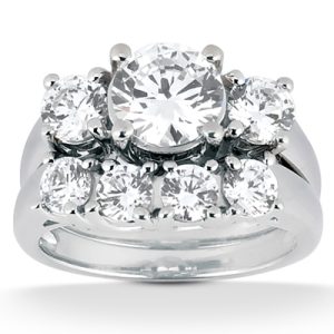 A polished silver ring features a large central diamond surrounded by five smaller diamonds.