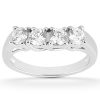A silver ring features four round, clear gemstones set in a row.