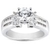 A silver engagement ring features a large round diamond surrounded by smaller diamonds on each side.