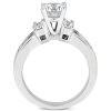 A three-stone engagement ring features a central round diamond flanked by two smaller diamonds, all set in white metal.