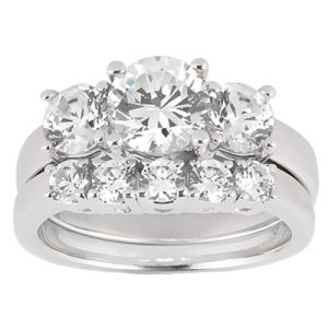 A silver ring featuring a cluster of three large round diamonds and a row of smaller diamonds along the band.