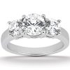 A three-stone diamond ring with a central large diamond flanked by two smaller diamonds on a polished metal band.
