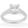 A silver ring with a large princess-cut diamond centerpiece and smaller stones along the band is displayed.