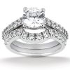 A diamond engagement ring with a large round stone and a split band adorned with smaller diamonds is displayed.