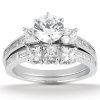 A silver engagement ring features a central round diamond surrounded by smaller square diamonds.