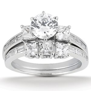 A silver engagement ring features a central round diamond surrounded by smaller square diamonds.