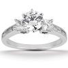 Three-stone engagement ring featuring a large round center diamond flanked by two smaller diamonds, set in a white metal band.