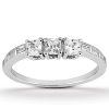 A silver ring features three prominent square-cut gemstones set in a row, accompanied by smaller rectangular stones along the band.