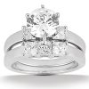 A diamond engagement ring featuring a large round center stone flanked by two smaller square diamonds.