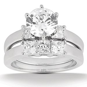A diamond engagement ring featuring a large round center stone flanked by two smaller square diamonds.