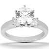 A silver engagement ring features a large central round diamond flanked by two smaller triangular diamonds.
