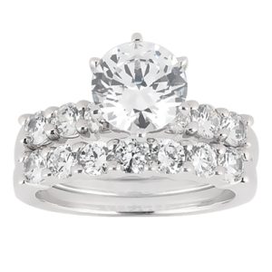 A silver engagement ring set featuring a large round center diamond and a pave band with multiple smaller diamonds.