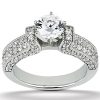 A silver ring features a large round diamond at the center, surrounded by smaller ornamental stones on the band.