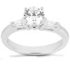 A silver engagement ring features a large round brilliant diamond in the center with two smaller baguette diamonds on each side.