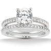 A silver engagement ring with a central round diamond surrounded by smaller diamonds on two bands.