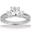 Three-stone engagement ring featuring a central round diamond surrounded by two smaller diamonds on a silver band.