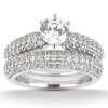 A diamond engagement ring with a round central stone and two intertwined bands set with small stones.