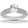 A silver ring featuring a central round diamond with smaller stones set along the band.