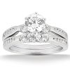 A silver engagement ring set features a large round diamond in the center, flanked by smaller diamonds on a split shank band.