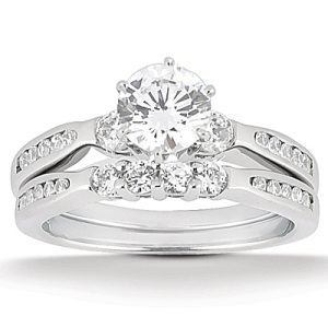 A silver engagement ring set features a large round diamond in the center, flanked by smaller diamonds on a split shank band.