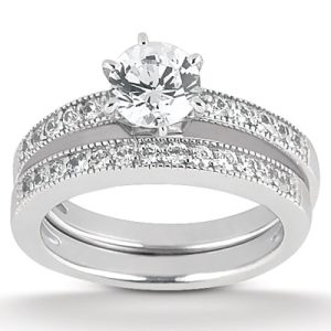 A diamond engagement ring set features a central round diamond surrounded by smaller stones on a silver band.