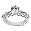 A silver engagement ring features a large central round diamond surrounded by four smaller diamonds on either side.