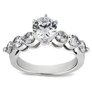A silver engagement ring features a large central round diamond surrounded by four smaller diamonds on either side.