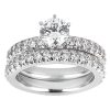 A diamond engagement ring set features a central round diamond surrounded by smaller diamonds on a white metal band.